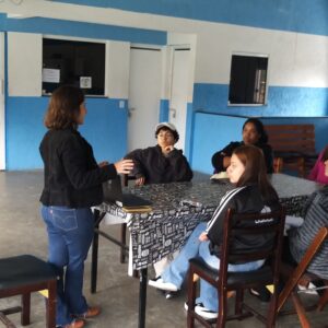 Uma professora dando aula a 5 alunos em uma mesa